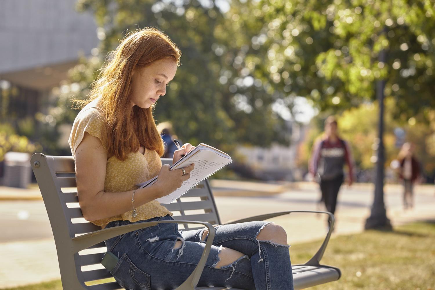 一位<a href='http://09uk.16300a.com'>bv伟德ios下载</a>学院的学生在校园里的长椅上读书.